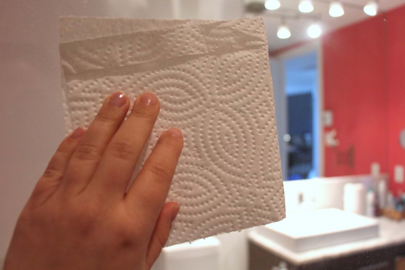 Main tenant un essuie-tout pour nettoyer la toilette