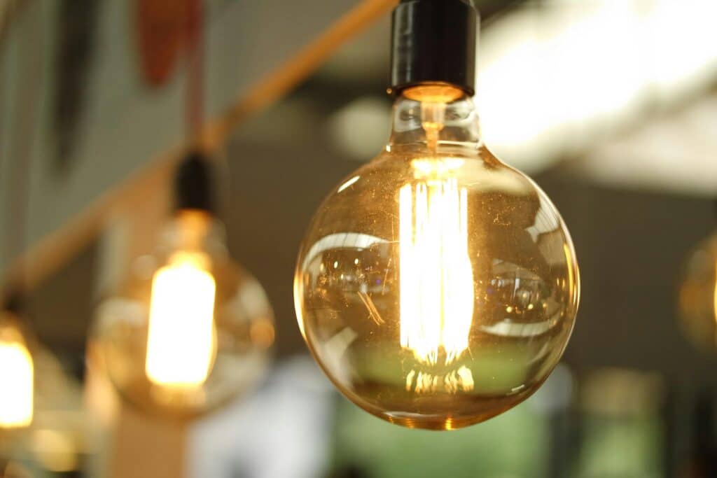Ampoule allumée suspendue, symbole d'engagement environnemental dans un espace moderne.